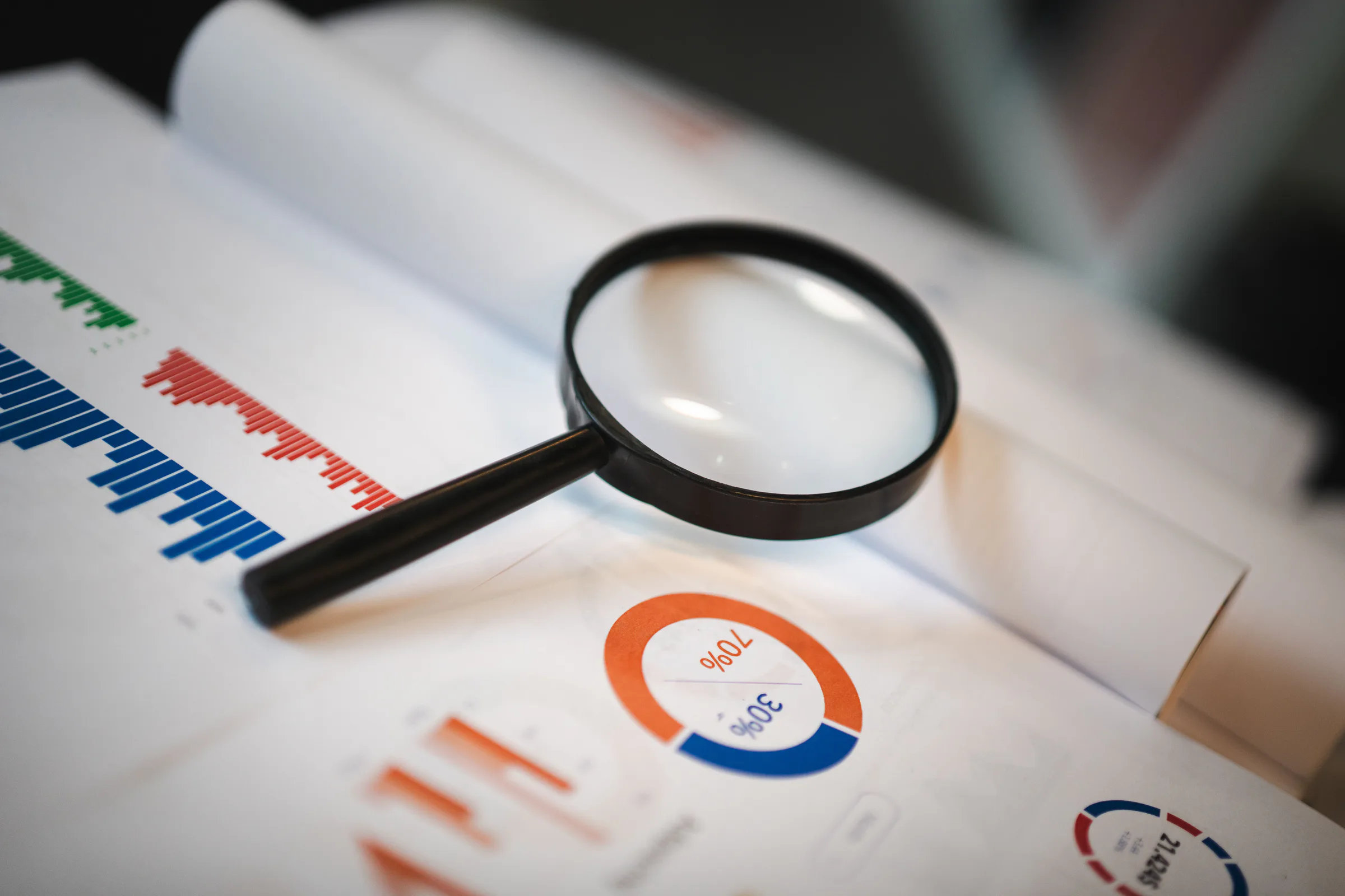 A magnifying glass isolating evidence in a set of business reports