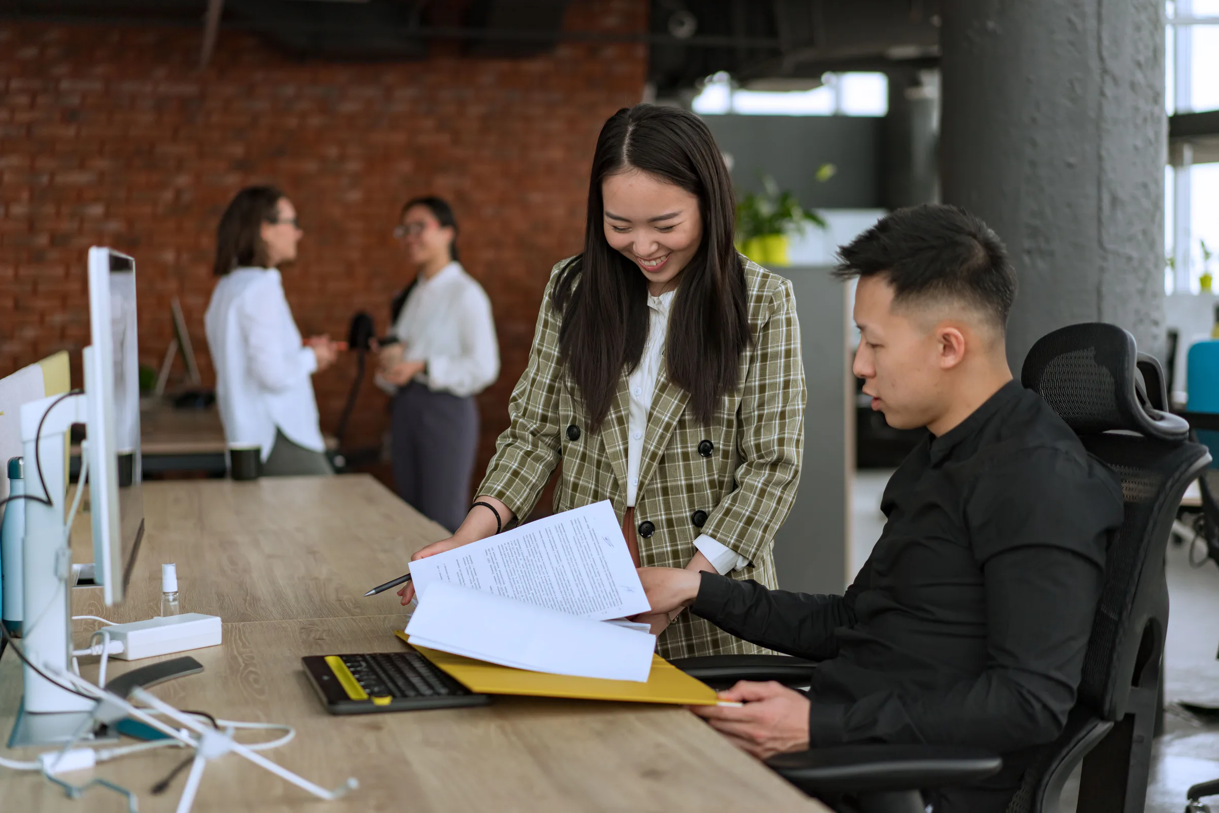Two colleagues resolving a document handoff at a shared desk