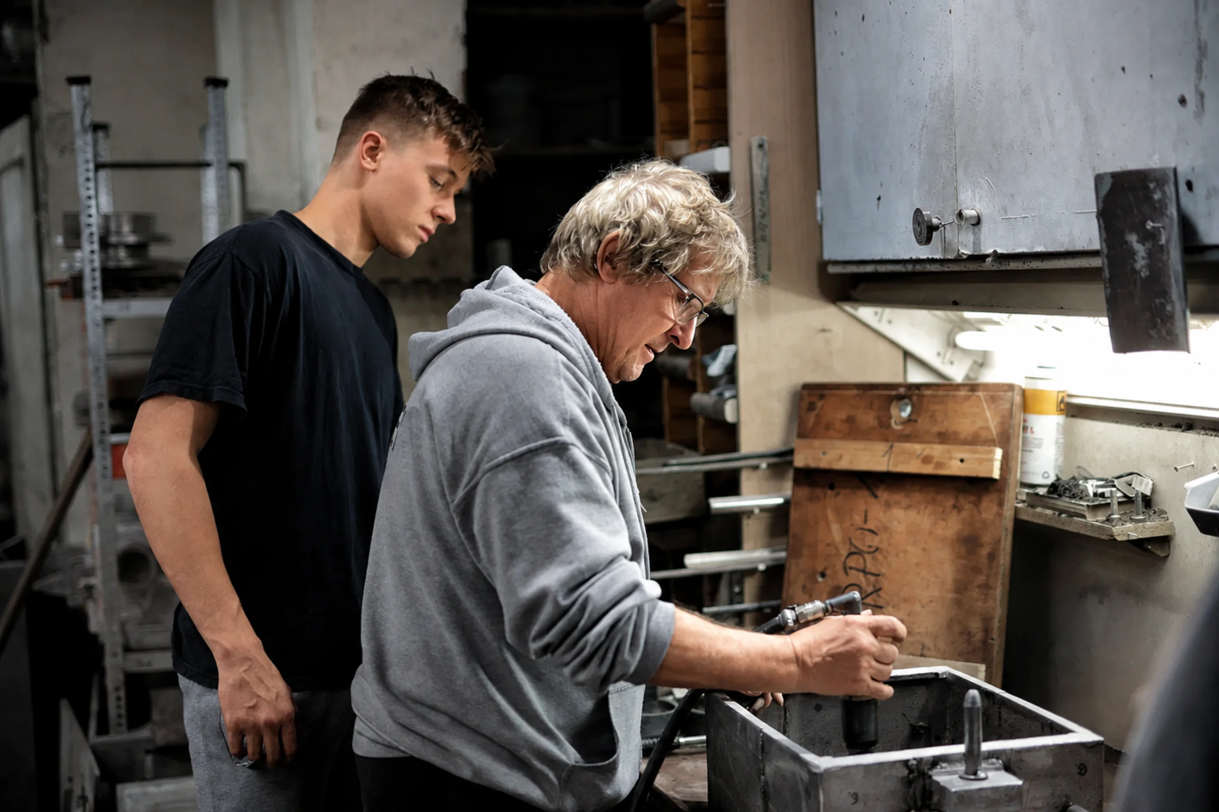 Two tradespeople sharing bench work during a handoff