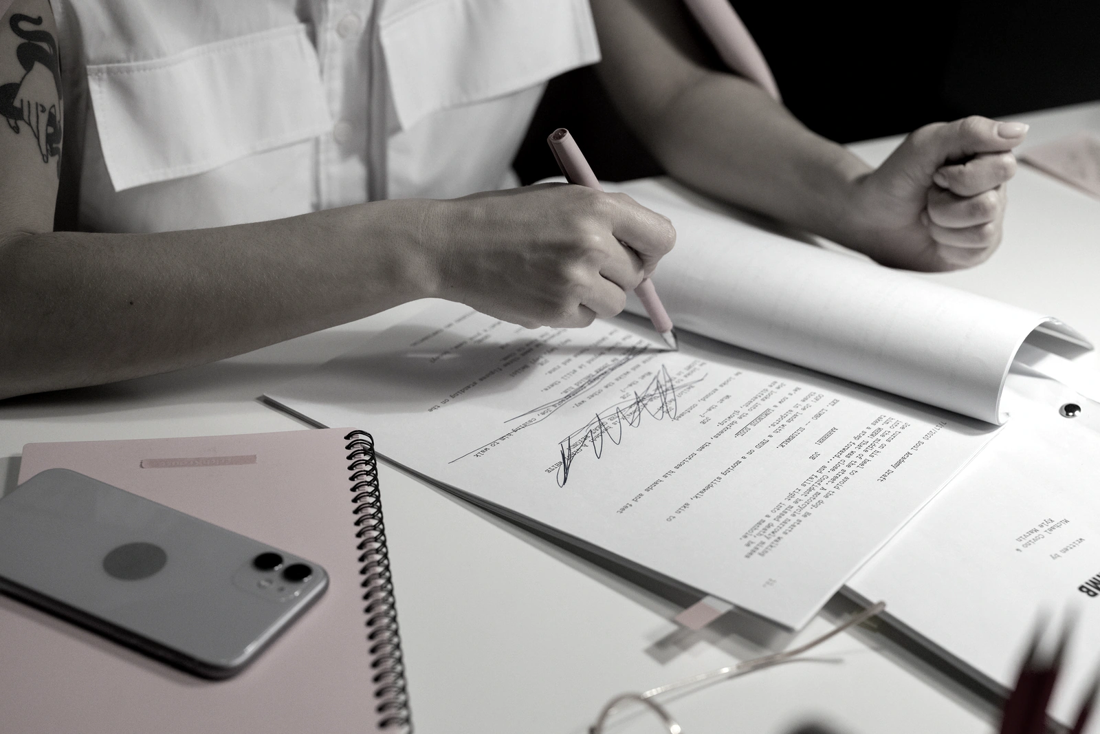 A hand marking up a bound working document with a pen, the artifact each phase of the engagement ends in